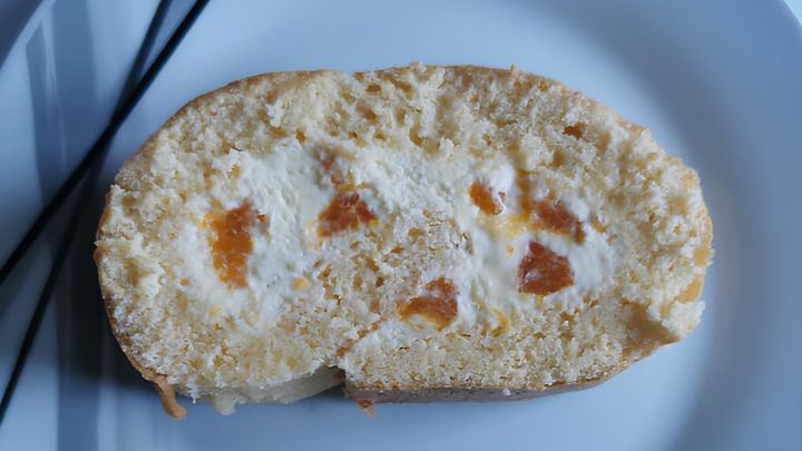 Fluffige Biskuitrolle mit Vanillepudding-Quark-F&uuml;llung und Mandarinen zum Verzehr auf dem Teller liegend.