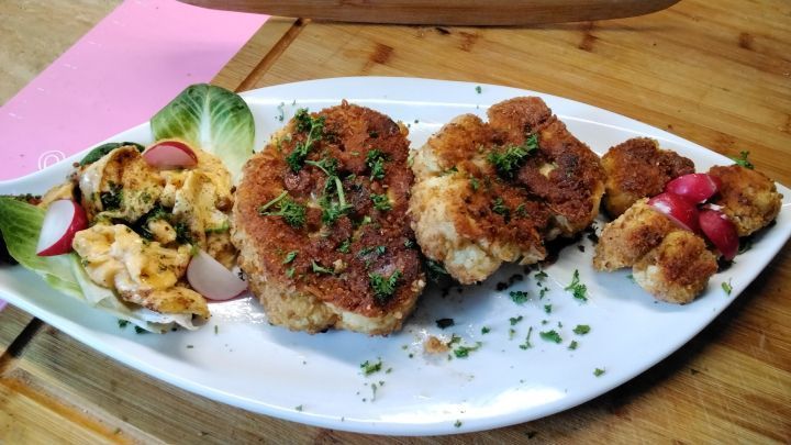 Blumenkohlschnitzel, die roh paniert und in Butterschmalz langsam gebacken werden, ohne vorher gegart zu werden.