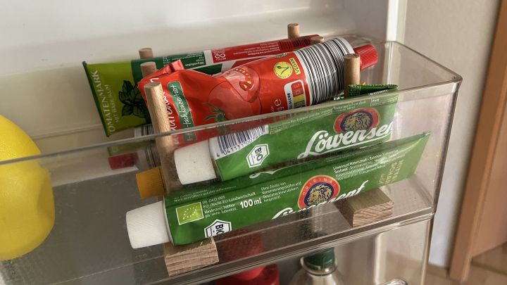 Der zuges&auml;gte Tellerhalter aus Holz dient hervorragend als Tuben-Organizer im K&uuml;hlschrank.