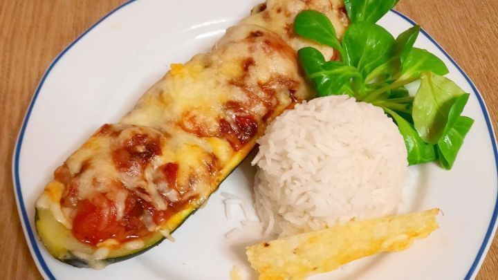 Vegetarisch gef&uuml;llte Zucchini mit K&auml;se &uuml;berbacken und Basmatireis als Beilage.