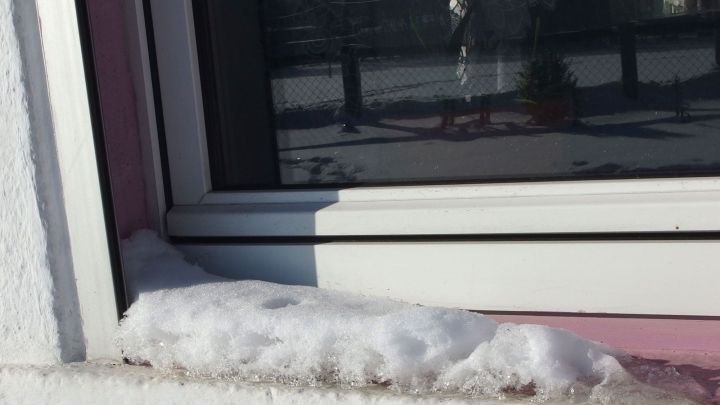 Ein Fenster zeigt Schnee auf der Fensterbank. Es ist Frostwetter, was das Fensterputzen erschwert.