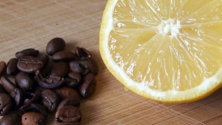 Eine halbierte Zitrone liegt neben einer Menge ger&ouml;steter Kaffeebohnen auf einem Holzbrett, was auf m&ouml;gliche Mittel gegen Kopfschmerzen hindeutet.