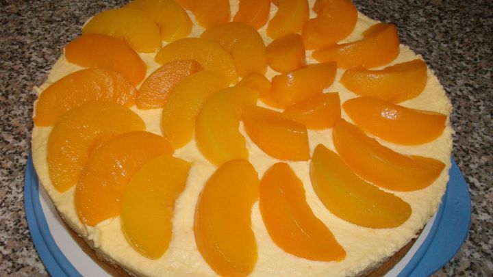Schneller Pfirsichkuchen mit Mamas Biskuit-Rezept, einer leckeren Paradiescreme und Pfirsichen als Topping.