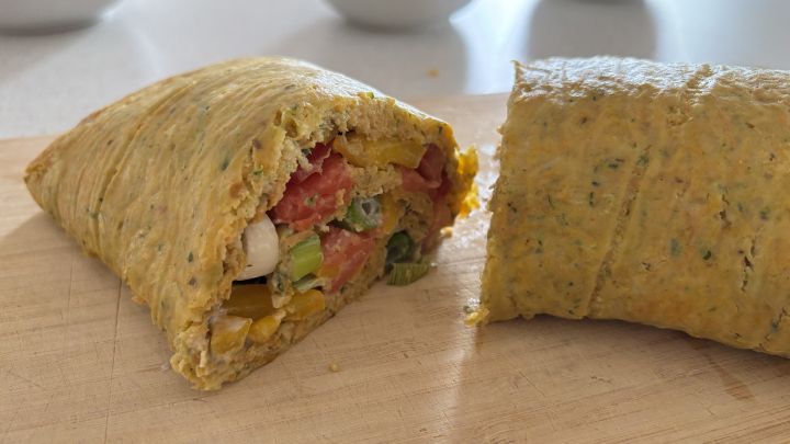 Low Carb Gem&uuml;serolle mit Ei, gef&uuml;llt mit buntem frischem Gem&uuml;se auf einem Holzbrett, in zwei St&uuml;cke geschnitten