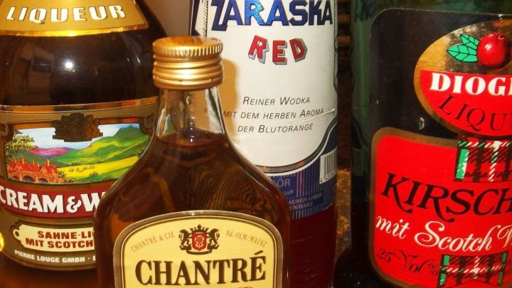 Eine Auswahl von Spirituosenflaschen steht auf einem Tisch, w&auml;hrend im Hintergrund eine erratisches Lichtspiel stattfindet.