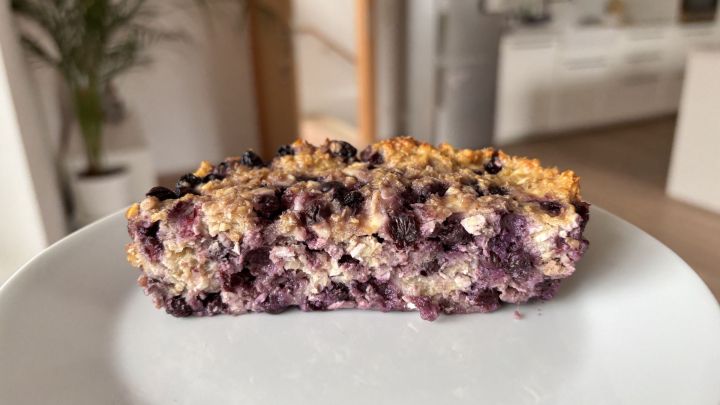 Baked Oats mit saftigen Heidelbeeren und H&uuml;ttenk&auml;se als proteinreiches Fr&uuml;hst&uuml;ck auf einem Teller in einer modernen K&uuml;che.