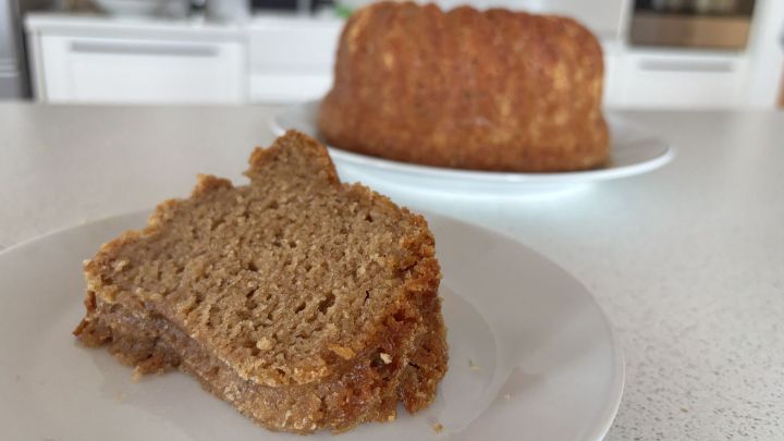 Saftiger Apfelgugelhupf mit Ahornsirup, angeschnittenes St&uuml;ck auf Teller in moderner K&uuml;che, goldbraune Krume und karamellisierte Kruste