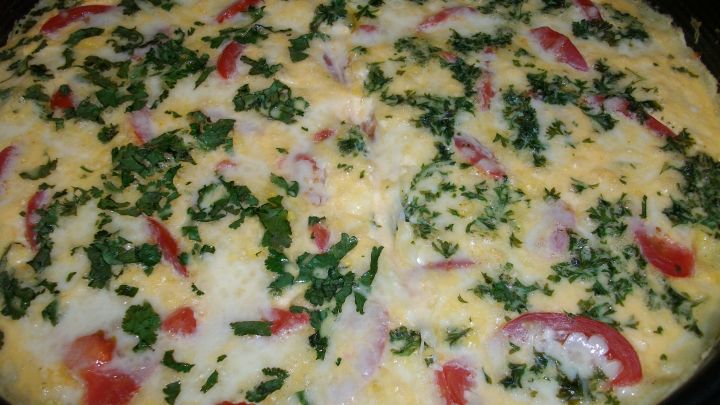 Kartoffelpizza ohne Mehl mit geschmolzenem K&auml;se, Tomatenst&uuml;cken und frischer Petersilie in einer runden Backform