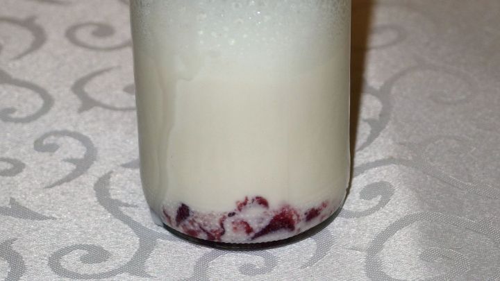 Ein Glas Marmeladen Shake zeigt eine schichtweise Kombination aus Milch und Fruchtmarmelade am Boden.