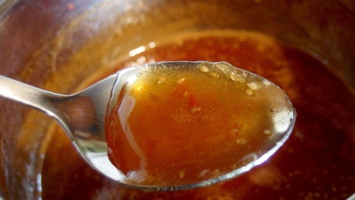 Ein L&ouml;ffel Orangen-J&auml;germeister-Gelee schimmert im Licht, w&auml;hrend er aus einem Topf entnommen wird, um serviert zu werden.