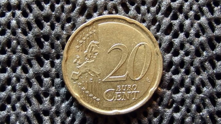Eine 20-Cent-M&uuml;nze liegt auf einer strukturierten, dunklen Unterlage. Es wird auf den Einkaufswagen-Bonus angespielt.