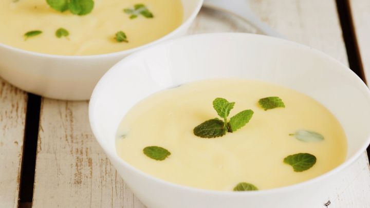 Pfefferminz-Pudding wird in wei&szlig;en Schalen serviert und ist mit frischen Minzbl&auml;ttern dekoriert, auf einem Holztisch.