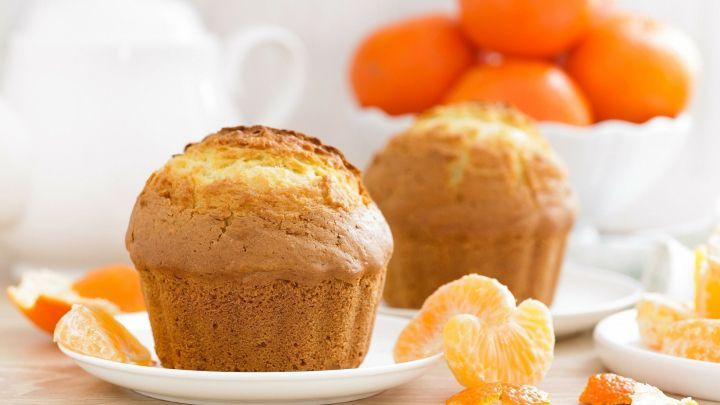 Saftige Tassenkuchen mit Mandarinen stehen auf Tellern, umgeben von frischen Mandarinen in einer hellen K&uuml;che.