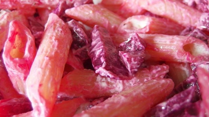 Ein bunter Nudelsalat aus rosa-pinken Nudeln und gemischtem Gem&uuml;se, appetitlich angerichtet f&uuml;r eine Mahlzeit.