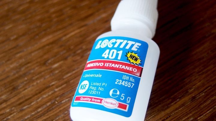 Ein kleiner Fl&auml;schchen Universalkleber steht auf einem Holzuntergrund, bereit zur Anwendung gegen Warzen.