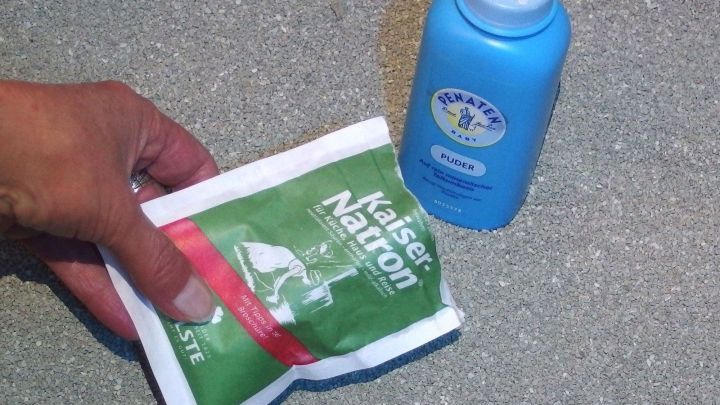 Eine Hand h&auml;lt eine Packung "Katzenstreu" neben einer blauen Flasche, um Ger&uuml;che aus dem Katzenklo zu bek&auml;mpfen.
