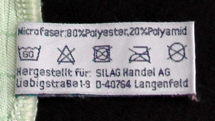 Ein Pflegeetikett zeigt die Zusammensetzung von Mikrofaser-Bettbez&uuml;gen, die weniger Staub enthalten.