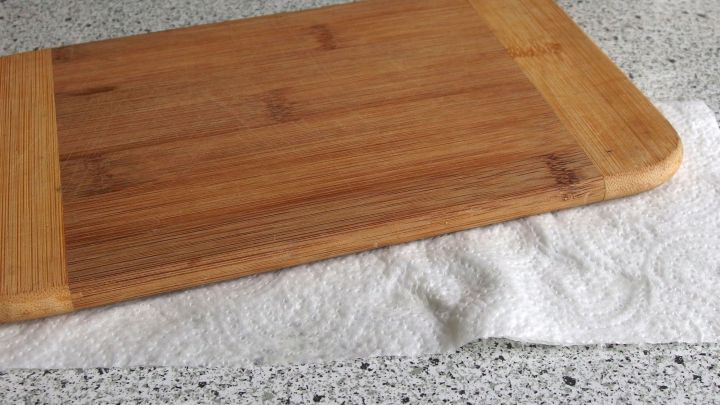 Ein Schneidebrett liegt stabil auf einem Handtuch, das auf einer modernen K&uuml;chentheke platziert ist.