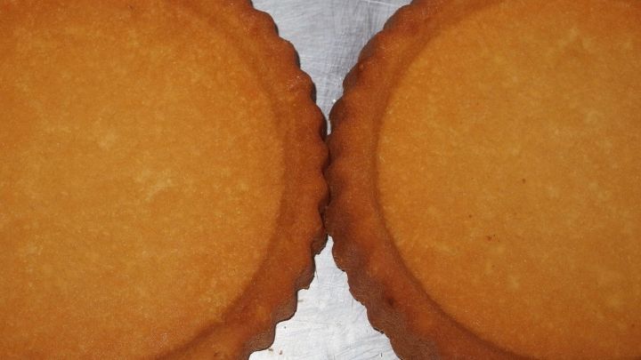 Zwei goldbraune Tortenb&ouml;den liegen nebeneinander auf einer Alufolie, bereit f&uuml;r die Weiterverarbeitung in einem Rezept.