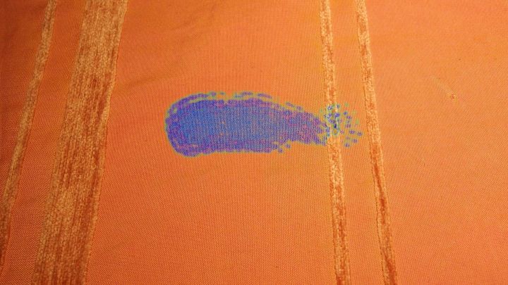 Ein blauer Fleck auf einem orangefarbenen Stoff, m&ouml;glicherweise verursacht durch Mineralwasser, liegt eindeutig im Mittelpunkt.