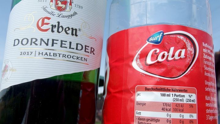 Two Flaschen nebeneinander: Links Rotwein "Erben Dornfelder 2017 Halbtrocken", rechts "surf Cola" mit N&auml;hrwertangaben.