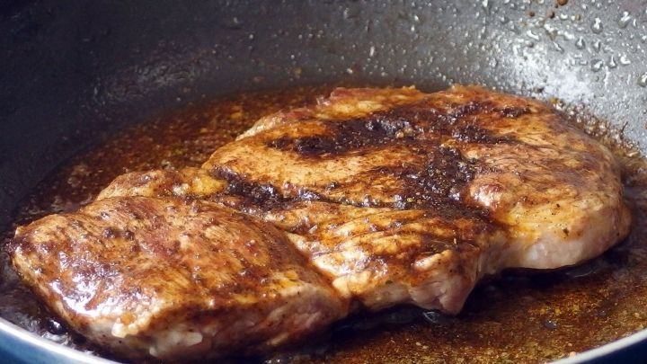 Ein gebratenes Schnitzel ruht in einer Pfanne, umgeben von sch&auml;umendem Fett, das ihm einen deftigen Geschmack verleiht.