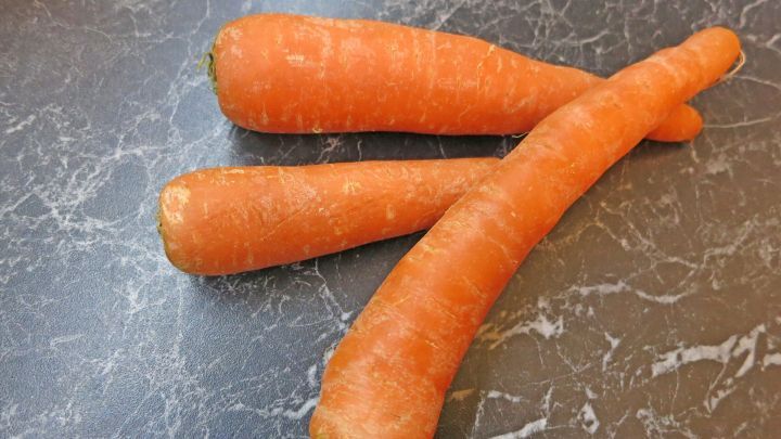 Frische Karotten liegen auf einer marmorierten Oberfl&auml;che, bereit zum Verarbeiten oder f&uuml;r einen gesunden Snack.