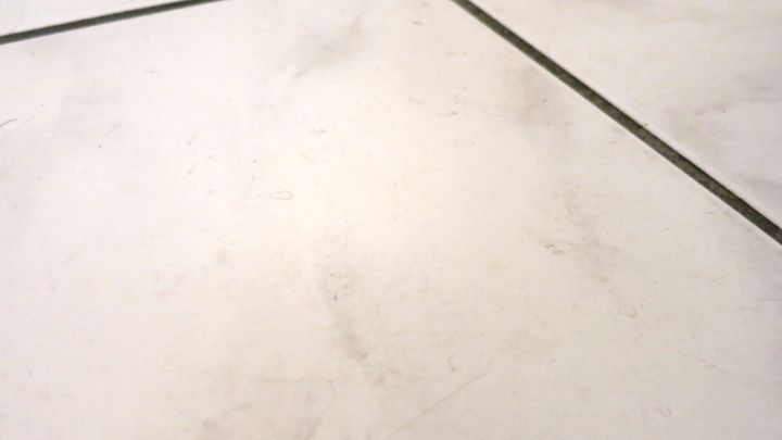 Ein schmutziger Boden mit Fliesen zeigt verschiedene Flecken. Das Bild vermittelt den Bedarf an Bodenreinigung mit Fensterreinigungskonzentrat.