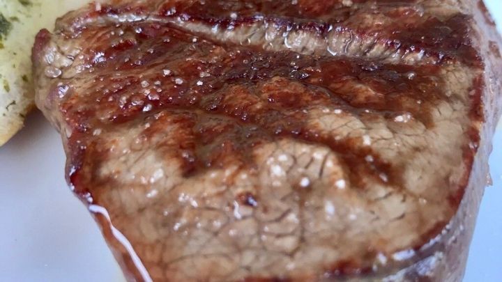 Saftiges, gegrilltes Steak auf einem wei&szlig;en Teller, umgeben von buntem Salat und einer Beilage, appetitlich angerichtet.