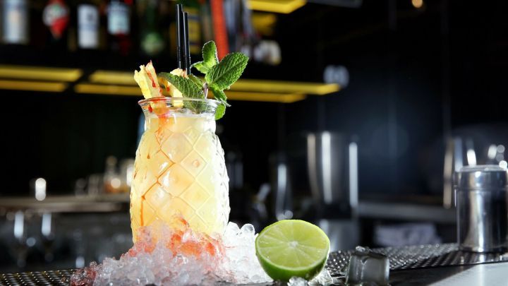 Ein erfrischender Malibu Maracuja-Cocktail steht auf Eis, garniert mit Minze und einer Limette, in einer stilvollen Bar.
