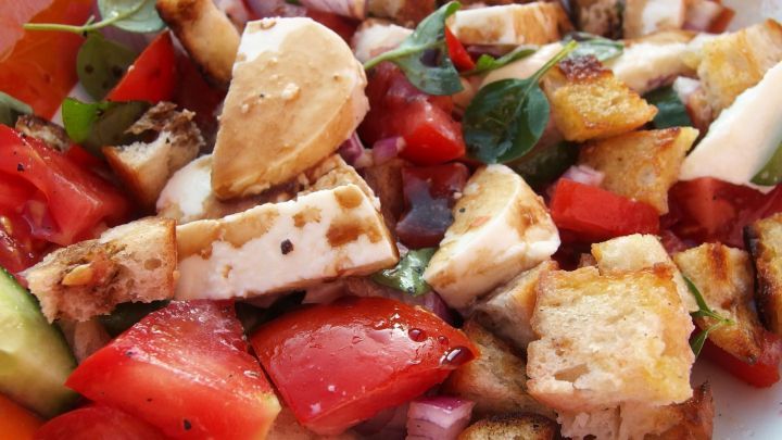 Ein bunter Brotsalat wird serviert, bestehend aus frischen Tomaten, Gurken und knusprigem Brotst&uuml;cken.