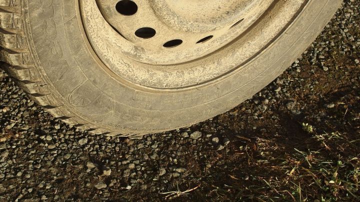 Ein Reifen liegt auf unebenem, kiesigem Boden und zeigt geringen Luftdruck, was das Spritsparen beeintr&auml;chtigen kann.