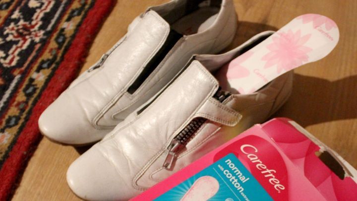 Wei&szlig;e Schuhe liegen auf einem Holzboden, daneben liegt eine Packung mit Slip-Einlagen f&uuml;r Schwitzf&uuml;&szlig;e im Sommer.