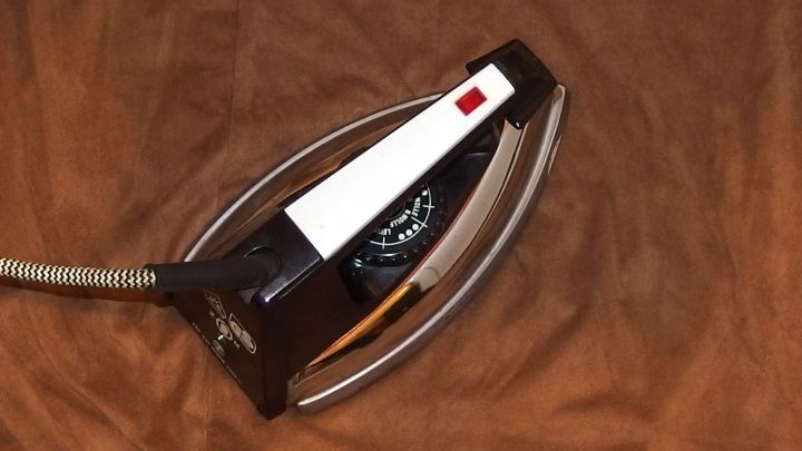 Ein B&uuml;geleisen liegt auf einem braunen Stoff, bereit, Seide zu b&uuml;geln, um Falten zu entfernen und Glanz zu verleihen.