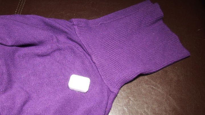 Ein lila Pullover liegt auf einem Tisch, w&auml;hrend ein Geschirrsp&uuml;ltab darauf platziert ist, um Flecken zu entfernen.