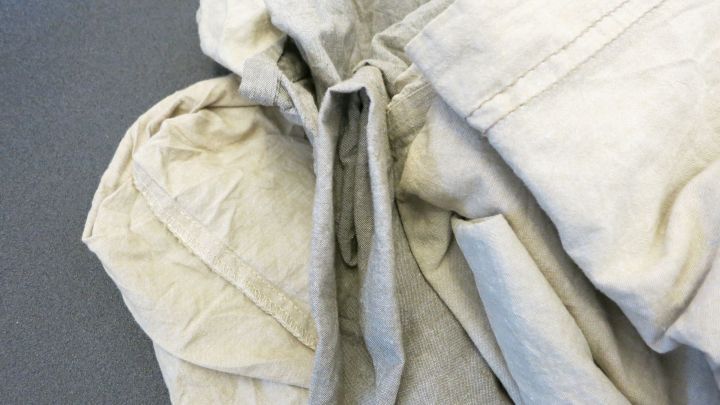 Ein paar Bettw&auml;sche-Teile liegen zusammengefaltet auf einem grauen Untergrund und sind bereit zum Waschen.