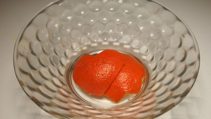 In einer gl&auml;sernen Schale liegt ein runder, orangefarbener Potpourri-Ball auf einem wei&szlig;en Untergrund und gibt einen frischen Duft ab.