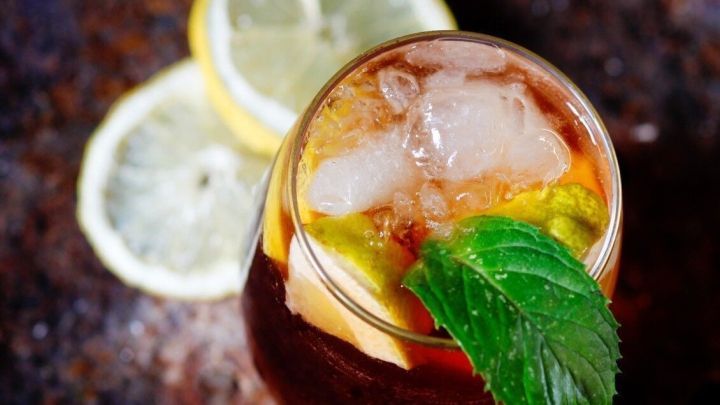 Ein erfrischender Sandsturm-Mini-Cocktail mit Eis und Minze steht auf einem rustikalen Tisch, umgeben von Zitronenscheiben.