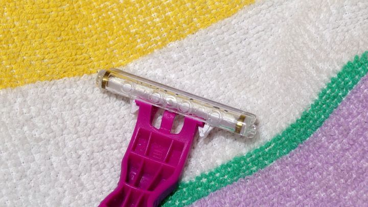 Ein Rasierer liegt auf einem bunten Handtuch und wartet darauf, verwendet zu werden, m&ouml;glicherweise nach der (Intim-)Rasur.