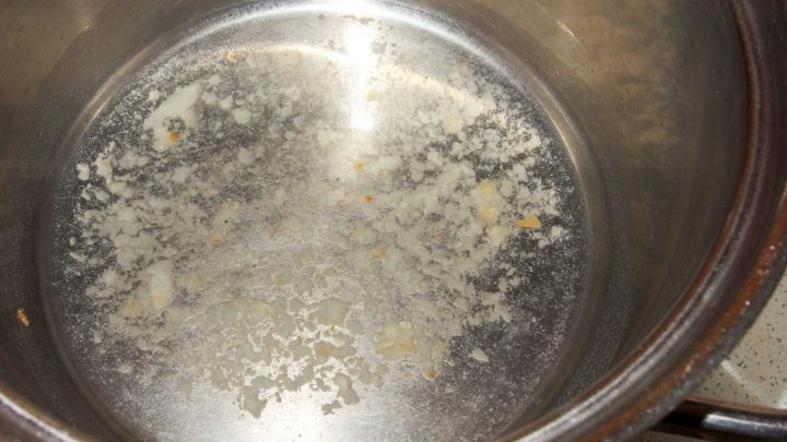 Ein Topf mit eingebranntem Belag wird in einer K&uuml;che gezeigt, bereit zur Reinigung mit Scheuerpulver.