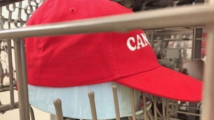 Eine rote Base Cap wird in einem Geschirrsp&uuml;ler auf einem oberen Regal gewaschen, um sie zu reinigen.