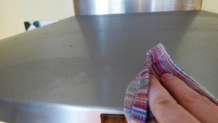 Ein Handtuch wischt &uuml;ber die glatte Oberfl&auml;che eines Herds, um Fett zu entfernen, in einer modernen K&uuml;chenumgebung.