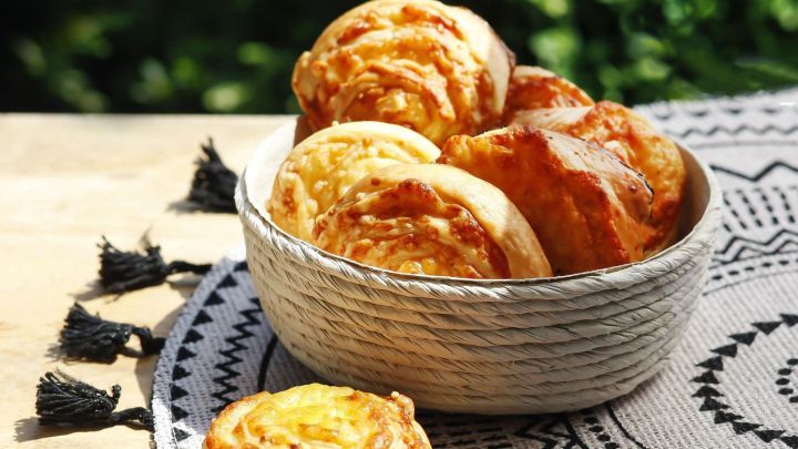K&auml;se-Taler in einer Sch&uuml;ssel zeigen goldbraune, appetitliche Geb&auml;ckst&uuml;cke auf einem dekorativen Tuch im Freien.