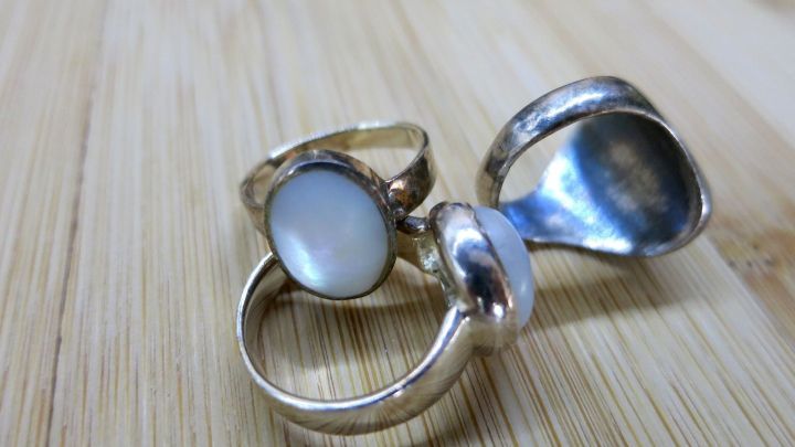 Drei angelaufene Silberringe liegen auf einer Holzoberfl&auml;che, bereit zur Reinigung mit saurer Milch.