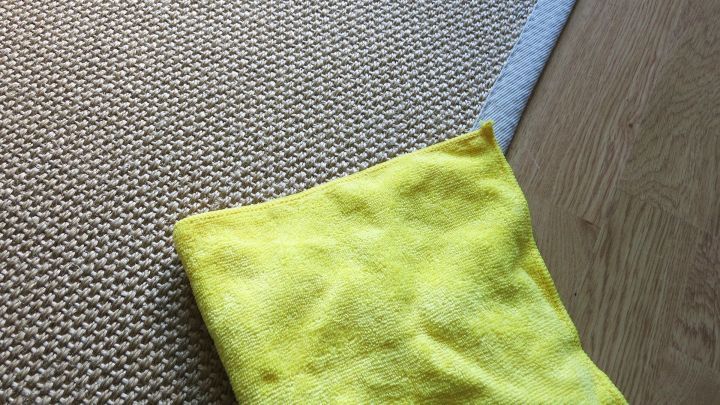 Ein gelbes Microfasertuch liegt auf einem Teppich und wird verwendet, um Flecken zu entfernen. Der Teppich ist hell und strukturiert.