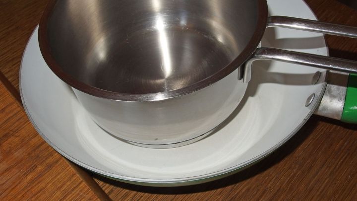 Eine gl&auml;nzende Edelstahl-Warmhaltekannen steht auf einem wei&szlig;en Teller, umgeben von einer Holzoberfl&auml;che.