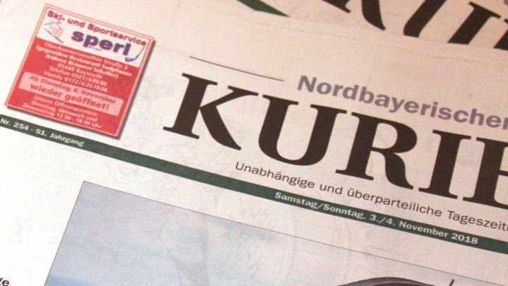 Zeitungspapier liegt auf einem B&uuml;geltisch, w&auml;hrend ein Hemd geb&uuml;gelt wird, um Kr&uuml;mel und Falten zu vermeiden.