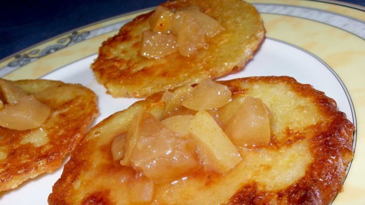 Knusprige Kartoffelpuffer liegen auf einem Teller, garniert mit fruchtigem Apfelmus, appetitlich angerichtet.