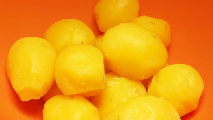 Pellkartoffeln in einer orangenen Sch&uuml;ssel, frisch gesch&auml;lt und gleich bereit zum Kochen oder Servieren.