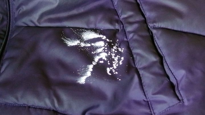 Auf einem dunklen, gepolsterten Stoff ist eine fettige Stelle zu sehen, die mit K&ouml;rperpuder behandelt wird.